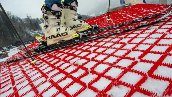 Ein Mann steht mit seinen Skiern auf einer Skipiste, die mit speziellen Kunststoff-Matten pr&auml;pariert wurde. Die Matten k&ouml;nnen das ganze Jahr &uuml;ber zum Skifahren verwendet werden. - &copy; Peter Kneffel/dpa