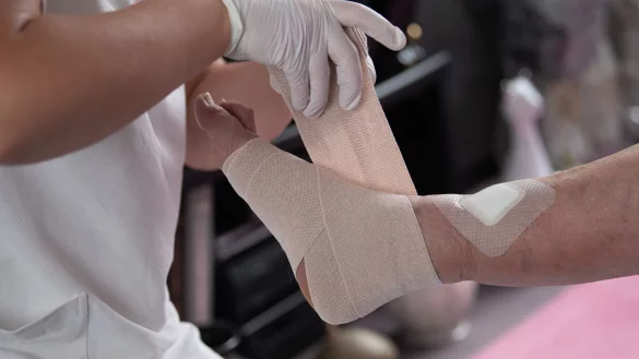 Eine Pflegefachkraft legt in der ambulanten Pflege einen Kompressionsverband an. - &copy; Sebastian Gollnow/dpa