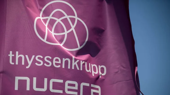 Auf einer Fahne vor dem Sitz in Dortmund steht „Thyssenkrupp Nucera“. - © Fabian Strauch/dpa/Symbolbild