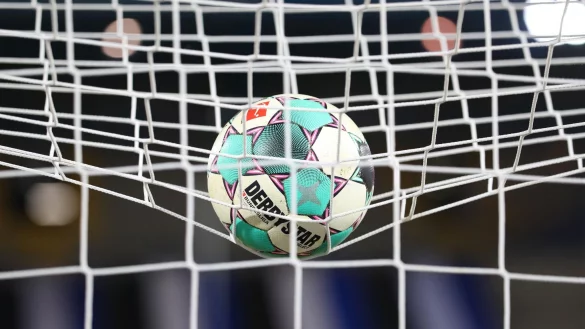 Ein Fußball liegt vor der Partie im Netz. - © Friso Gentsch/dpa/Symbolbild