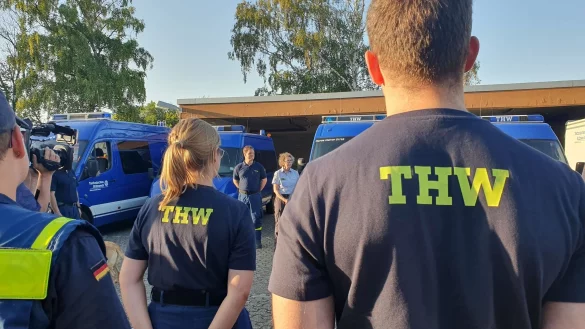 Einsatzkräfte vom Technischen Hilfswerk THW stehen bei einer Besprechung zusammen. - © Sascha Thelen/dpa