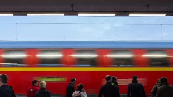 Bahnreisende warten in Bochum (Nordrhein-Westfalen) am Hauptbahnhof auf einem Gleis w&auml;hrend ein Zug vorbeif&auml;hrt. - &copy; picture alliance / dpa