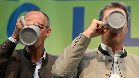 CDU-Chef Friedrich Merz (l) und Bayerns Ministerpr&auml;sident Markus S&ouml;der (CSU) trinken beim Politischen Fr&uuml;hschoppen Gillamoos auf der B&uuml;hne aus Bierkr&uuml;gen. - &copy; Sven Hoppe/dpa
