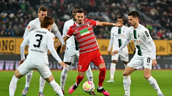 Augsburgs Mergim Berisha (M) kämpft mit Ko Itakura (l) und Julian Weigl (r) von Mönchengladbach um den Ball. - © Peter Kneffel/dpa