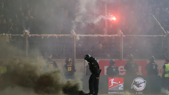 Bieldefelder Fans werfen Leuchtraketen aug das Spielfeld, ein Polizist tritt eine Nebelbombe aus. - &copy; J&ouml;rg Halisch/dpa