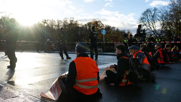 Klimaaktivisten einer Umweltschutzbewegung sitzen auf einer Stra&szlig;e. - &copy; Lennart Preiss/dpa/Symbolbild