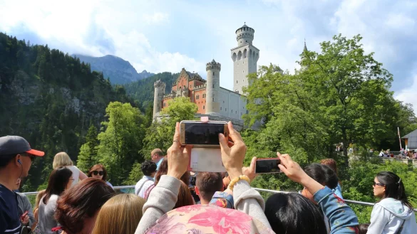Touristen stehen auf einer Aussichtsplattform unterhalb des Schlosses Neuschwanstein. - &copy; picture alliance / dpa