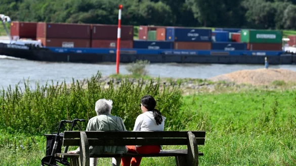 Spazierg&auml;nger sitzen am Ufer des Rheins und genie&szlig;en die Sonne. - &copy; Roberto Pfeil/dpa