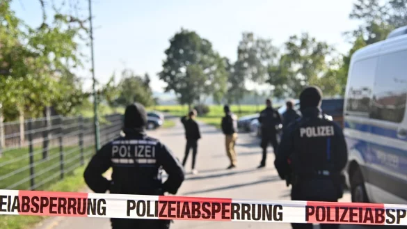 Einsatzkr&auml;fte der Polizei stehen hinter einer Polizeiabsperrung nach einer Razzia in Hesselbronn. - &copy; Jan-Philipp Strobel/dpa