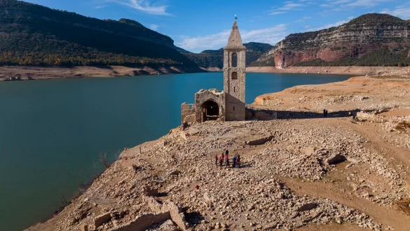 Eine Kirche und die Überreste eines alten Dorfes, die normalerweise vom Wasser bedeckt werden, sind am Stausee von Sau in Katalonien zu sehen. - © Emilio Morenatti/AP