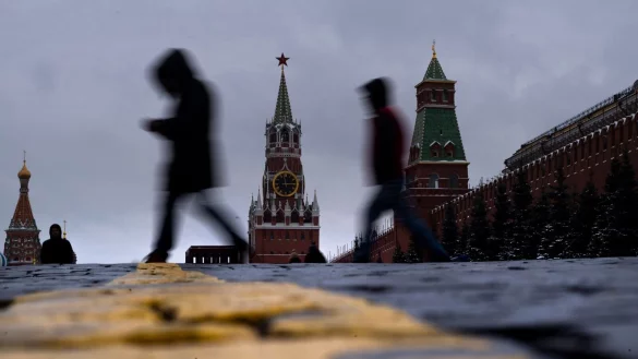 Menschen gehen vor dem Erl&ouml;serturm im Kreml (M) &uuml;ber den Roten Platz. - &copy; Alexander Zemlianichenko/AP/dpa