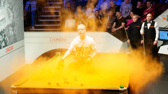 Ein &laquo;Just Stop Oil&raquo;-Demonstrant springt auf den Tisch und wirft orangenes Pulver w&auml;hrend des Spiels. - &copy; Mike Egerton/PA Wire/dpa