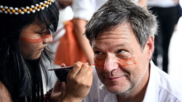 Ein Symbol des Willkommens und des Schutzes: Ein Mädchen malt Bundeswirtschaftsminister Robert Habeck mit einer rötlichen Naturfarbe ein Zeichen unter die Augen. - © Britta Pedersen/dpa