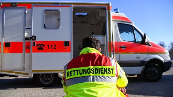 «Rettungsdienst» steht auf der Jacke eines Mannes vor einem Rettungswagen der Feuerwehr. - © Jens Kalaene/dpa/Symbolbild