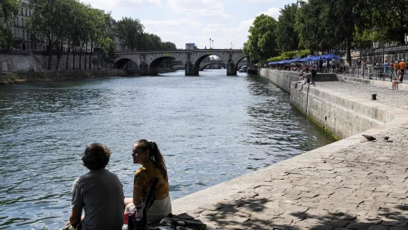 Zwei junge Leute sitzen am Ufer der Seine in Paris. - &copy; Alain Jocard/AFP/dpa