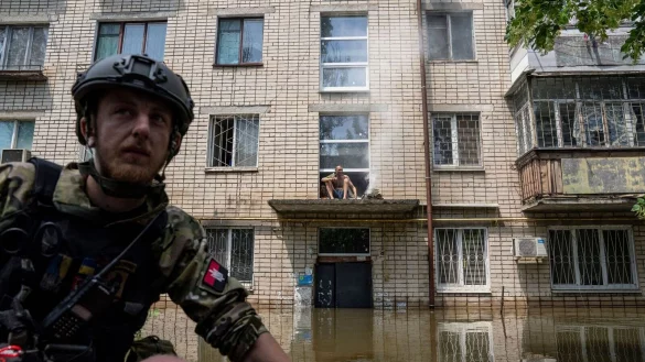 Ein Mann kocht auf einem offenen Feuer auf einer Veranda vor dem Eingang eines mehrst&ouml;ckigen Geb&auml;udes in einem &uuml;berfluteten Viertel. - &copy; Evgeniy Maloletka/AP/dpa