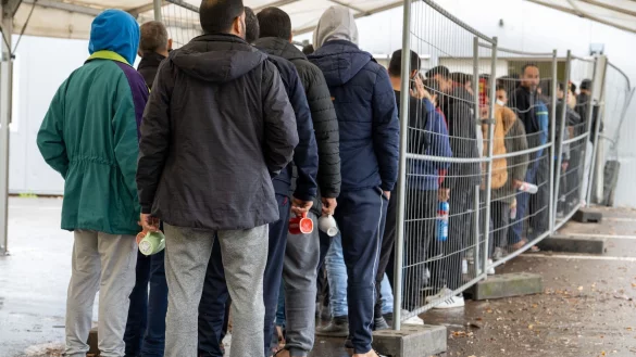 Fl&uuml;chtlinge warten in einer Landeserstaufnahmestelle in einer Schlange. Der Landkreistag spricht sich f&uuml;r die Pr&uuml;fung von Asylantr&auml;gen an den EU-Au&szlig;engrenzen und die Beendigung freiwilliger Aufnahmeprogramme aus. - &copy; Stefan Puchner/dpa