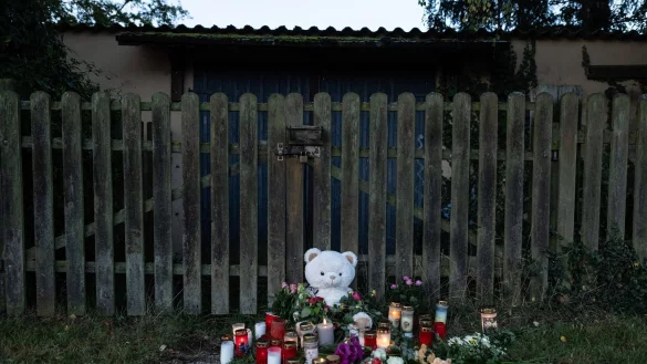 Kerzen, Blumen und ein großer Plüschteddy vor einem Zaun am Fundort der Leiche einer 14-Jährigen. - © Swen Pförtner/dpa