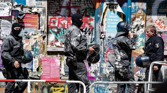 Mit Farbe beworfene Polizeibeamte verlassen das Haus Nr. 94 in der Rigaer Stra&szlig;e in Berlin. - &copy; Paul Zinken/dpa-Zentralbild/dpa