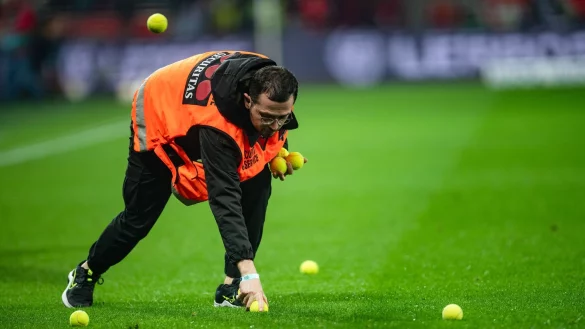 Ein Ordner sammelt Tennisb&auml;lle auf, die K&ouml;lner Fans au den Rasen geworfen haben. - &copy; Marius Becker/dpa