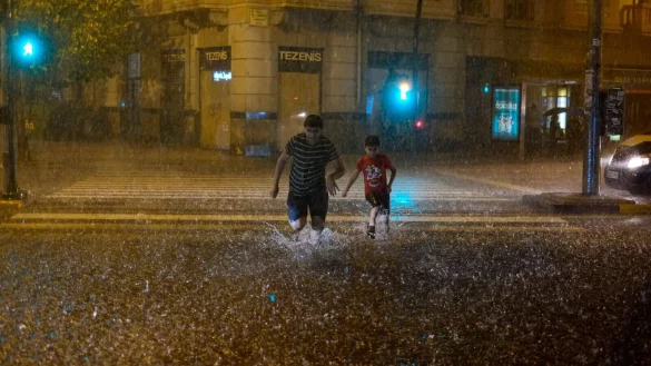 Menschen &uuml;berqueren bei starkem Regen eine &uuml;berschwemmte Stra&szlig;e in Pamplona. - &copy; Alvaro Barrientos/AP