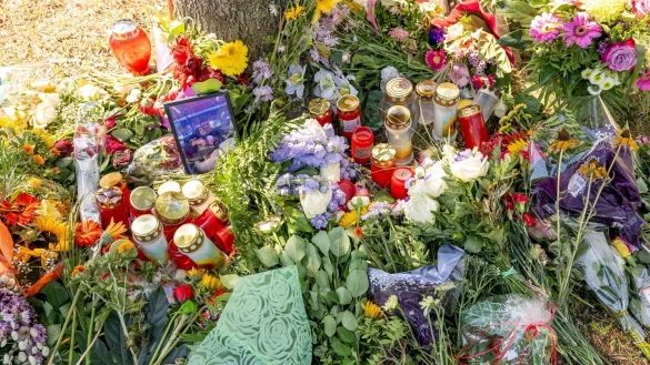 Blumen, Kerzen und Bilder liegen an einem Baum, in dessen Nähe am 17. August 2022 die tote Frau in einem Auto entdeckt wurde. - © Peter Kneffel/dpa/Archiv