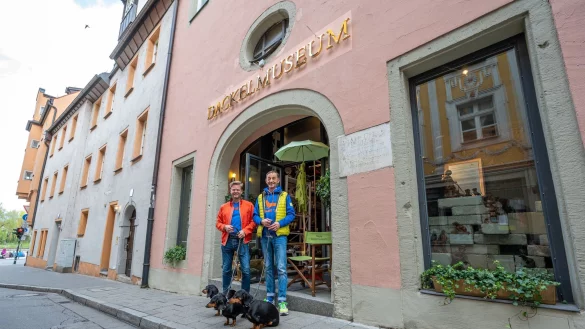 Seppi K&uuml;blbeck (r) und Oliver Storz mit ihren drei Dackeln: Wegen eines Streits mit der Passauer Stadtverwaltung ist sind sie mit ihrem Dackelmuseum nun nach Regensburg umgezogen. - &copy; Armin Weigel/dpa