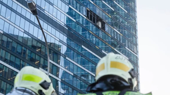Feuerwehrleute stehen neben dem besch&auml;digten Hochhaus im Gesch&auml;ftsviertel Moskwa City. - &copy; Uncredited/AP/dpa