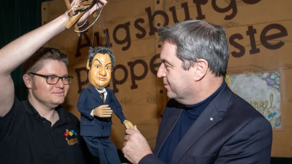 Markus S&ouml;der (r, CSU), Ministerpr&auml;sident von Bayern, gibt in der Augsburger Puppenkiste einer S&ouml;der-Marionette die Hand. - &copy; Stefan Puchner/dpa