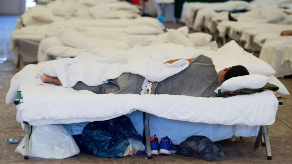 ARCHIV - Ein Gefl&uuml;chteter liegt einem Feldbett in einem Zelt einer Erstaufnahmeeinrichtung. - &copy; picture alliance/dpa/Symbolbild