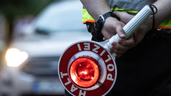 Ein Polizist hält bei einer Verkehrskontrolle eine Winkerkelle in der Hand. - © Paul Zinken/dpa/ZB/Symbolbild