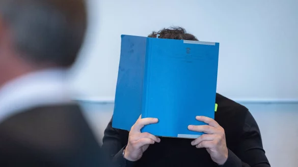 Einer der Hauptangeklagten versteckt zu Beginn des Prozess wegen Betrugs mit Corona-Tests sein Gesicht. - &copy; Rolf Vennenbernd/dpa