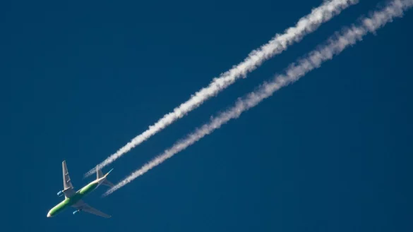 Ein Flugzeug hinterlässt Kondensstreifen am Himmel. Spätestens Mitte des Jahrhunderts soll schließlich mit grünem Wasserstoff geflogen werden. - © Julian Stratenschulte/dpa