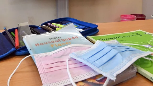 Masken liegen in einem Klassenzimmer auf einem Schulbuch. - &copy; Patrick Pleul/dpa-Zentralbild/dpa/Symbolbild