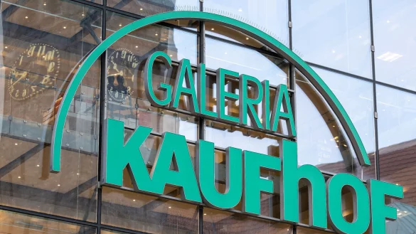 Die Uhr des Neuen Rathauses spiegelt sich im Logo der Galeria Kaufhof. - © Hendrik Schmidt/dpa/Archivbild