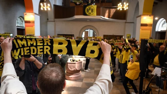 Gemeindereferent Karsten Haug h&auml;lt beim Gottesdienst in der Gr&uuml;ndungskirche des BVB seinen BVB-Fanschal in die H&ouml;he. - &copy; Federico Gambarini/dpa