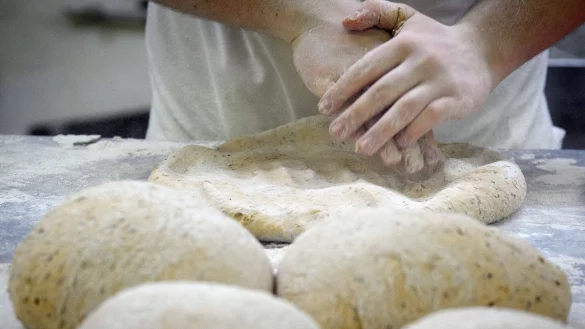 Ein B&auml;cker formt in der Backstube auf einer mit Mehl best&auml;ubten Arbeitsplatte den Teig. - &copy; Soeren Stache/dpa/Symbolbild