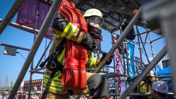 Der Feuerwehrmann Philipp Reumann von der Freiwilligen Feuerwehr Eckwarden steigt bei der &laquo;Firefighter Combat Challenge&raquo; in Bremerhaven mit einem Schlauch auf einen Turm. - &copy; Focke Strangmann/dpa