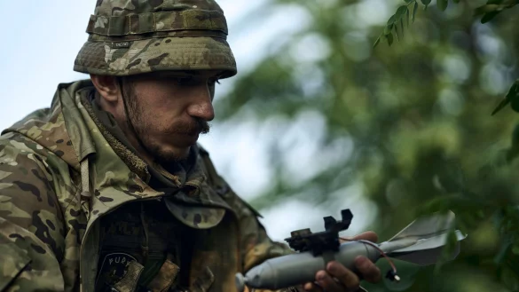 Ein ukrainischer Soldat l&auml;dt eine Bombe auf eine Drohne. - &copy; LIBKOS/AP