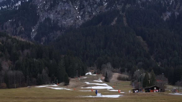 Reste von Kunstschnee auf einer Skipiste in grüner Landschaft. - © Karl-Josef Hildenbrand/dpa