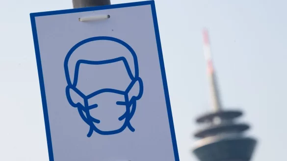 Ein Piktogramm weist auf das Einhalten der Maskenpflicht hin. - © Federico Gambarini/dpa/Archivbild
