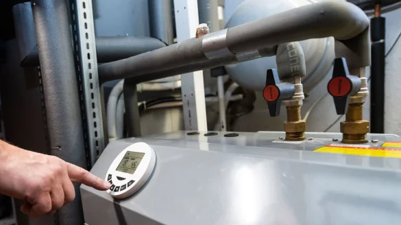 Ein Mann bedient eine Luftw&auml;rmepumpe, die im Keller eines Wohnhauses steht. - &copy; Silas Stein/dpa