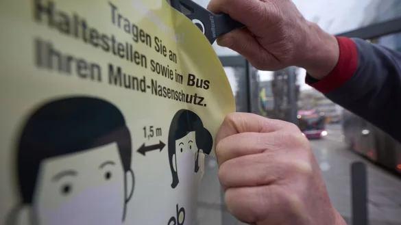 Ein Mitarbeiter der Koblenzer Verkehrsbetriebe entfernt an einer Haltestelle einen Aufkleber, der die Fahrg&auml;ste zum Tragen von Masken auffordert. - &copy; Thomas Frey/dpa