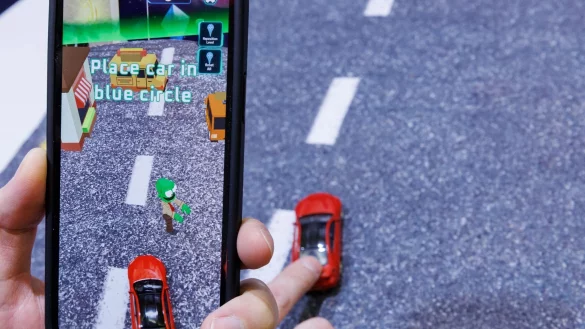 Mittels Smartphone, welches ein reales Spielzeugauto mit der Kamera erfasst, wird beim Spiel &laquo;Zombie Crasher AR&raquo; von Augmented Robotics eine virtuelle Stra&szlig;enszene dargestellt. - &copy; Daniel Karmann/dpa