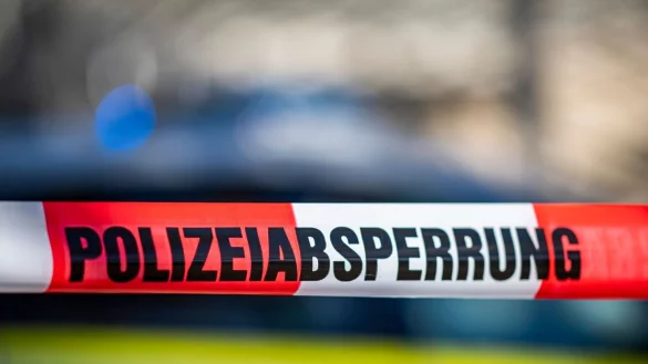 Ein Absperrband mit der Aufschrift &laquo;Polizeiabsperrung&raquo; ist vor einem Polizeiwagen aufgespannt. - &copy; David Inderlied/dpa/Illustration