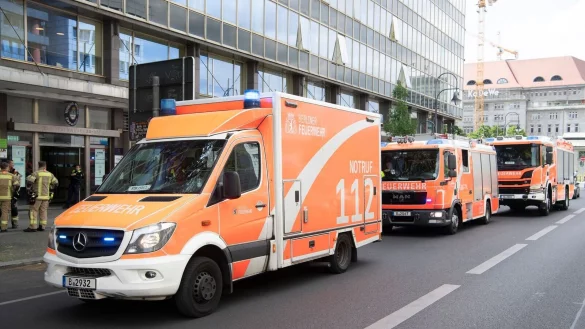 Einsatzfahrzeuge der Feuerwehr stehen vor dem mehrgeschossigen Gebäude, in dem es zu einem tödlichen Unfall mit einem Paternoster gekommen war. - © Paul Zinken/dpa