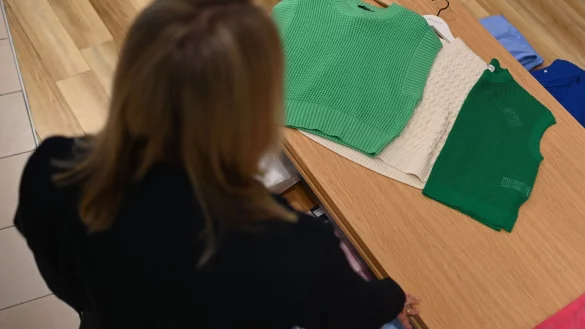 Eine Frau schaut sich drei Pullunder auf einem Verkaufstisch an. - © Lars Klemmer/dpa