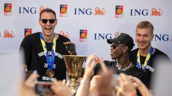 Kapit&auml;n Dennis Schr&ouml;der h&auml;lt beim Empfang den Pokal. Hinter ihm stehen Johannes Voigtmann und Niels Giffey. - &copy; Helmut Fricke/dpa