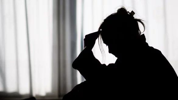 Silhouette einer Frau vor einer hellen Fensterfront - © Julian Stratenschulte/dpa