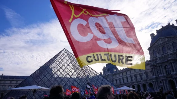 Angestellte zeigen eine Flagge der Gewerkschaft CGT vor dem Louvre, nachdem sie f&uuml;r einen Streik gestimmt haben. - &copy; Michel Euler/AP/dpa